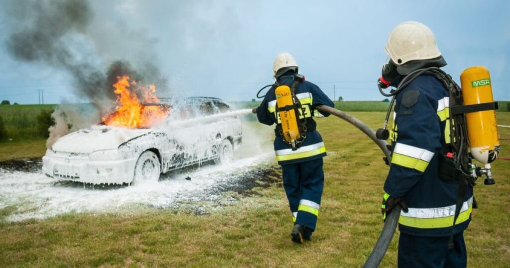Fire service men pouring water on a burning car