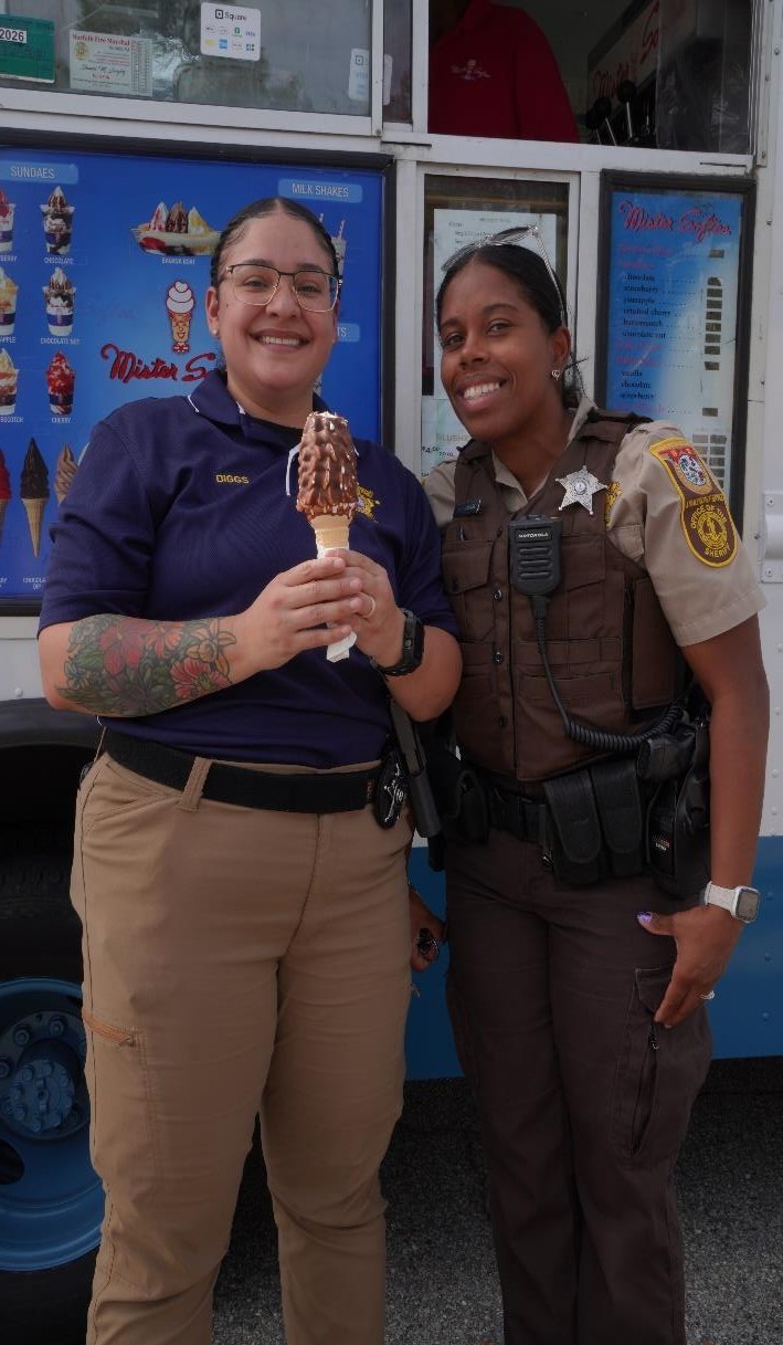 One Cooper Hurley staff member holding a cone icecream posing with a law enforcement officer