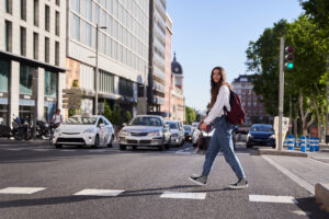 Young woman walking across the street in crosswalk in downtown historic area