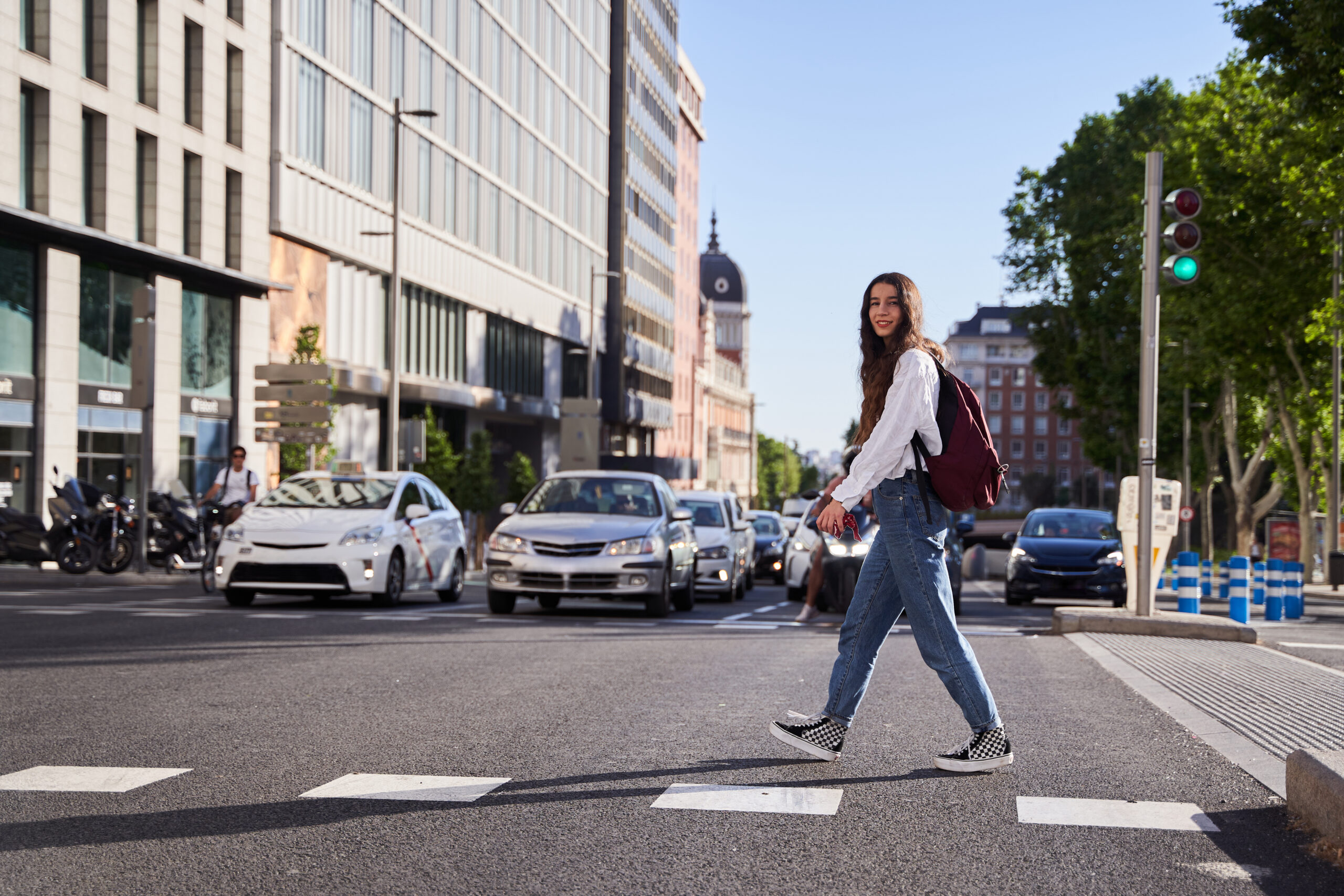 Young woman walking across the street in crosswalk in downtown historic area